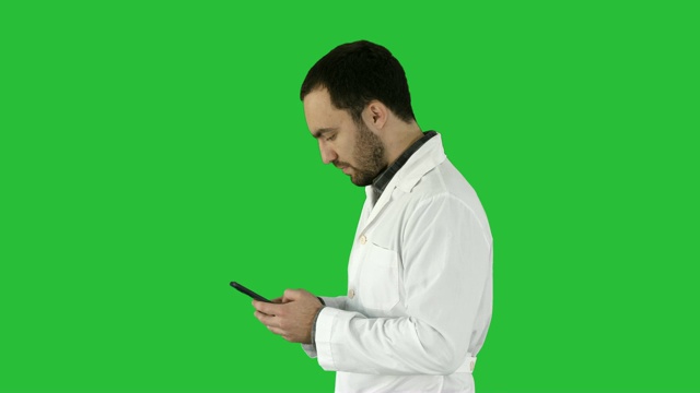 走路的医生或护士用绿屏手机发短信，颜色键视频素材