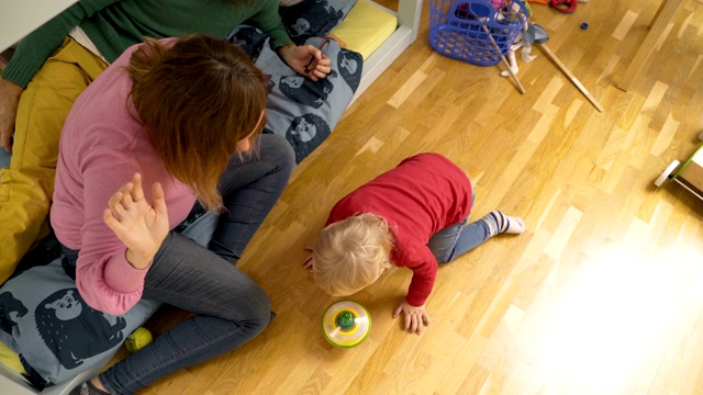 早上，一家人在孩子的房间里玩纺纱玩具。视频下载