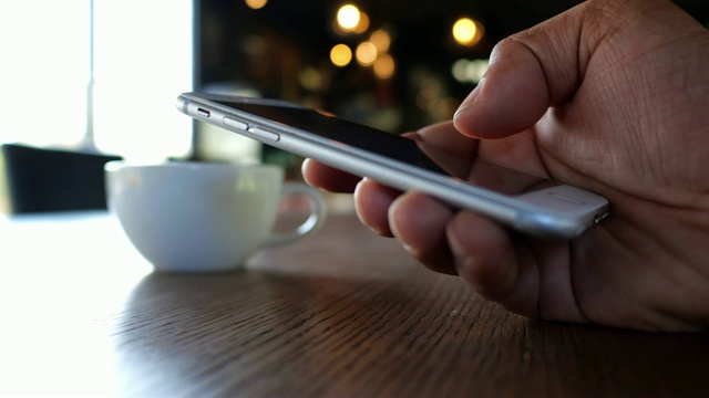 一名男子在咖啡店拿着智能手机视频素材