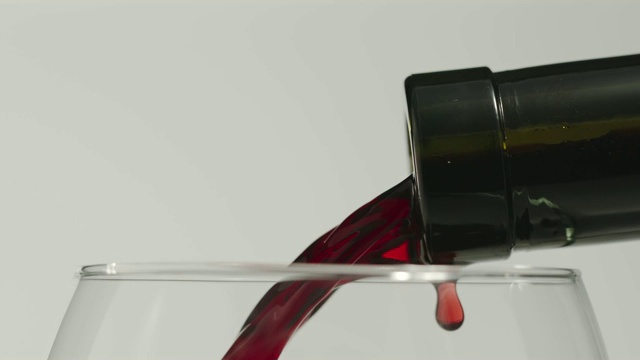 慢动作:将红酒从瓶中倒入玻璃杯-宏观，侧视图视频下载