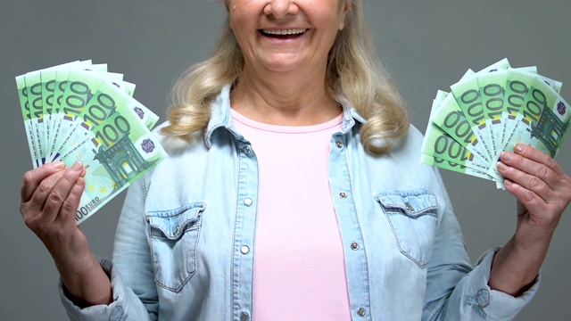 快乐成熟的女人展示欧元钞票，轻松的银行信贷，养老金财富视频素材