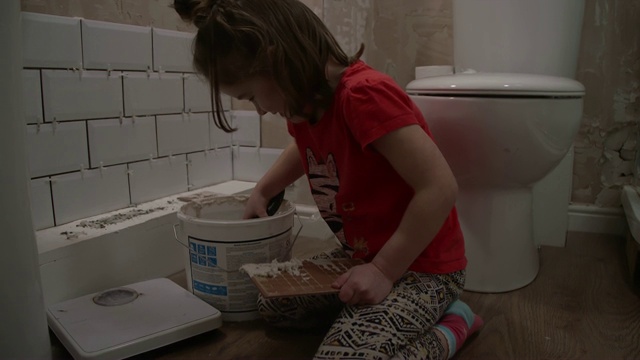 年轻的女孩学习如何墙壁瓷砖帮助她的父亲的家装修视频素材