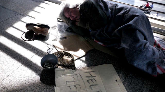 一个穿着脏衣服睡在街上寻求帮助的无家可归的老人视频下载