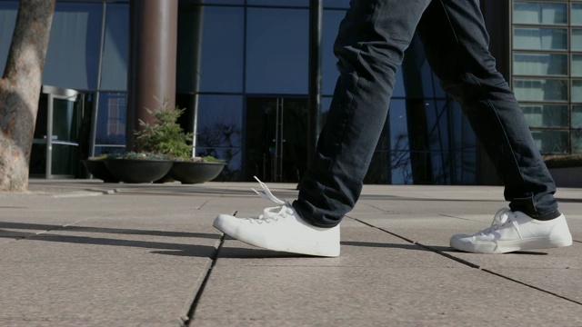 一名成年男子的腿部轮廓行走在首尔建筑前的人行道上视频下载