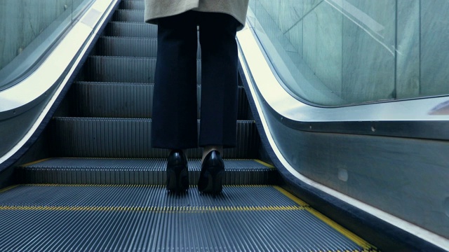 在首尔，一个成年妇女爬上地下通道的自动扶梯的腿部后视图视频下载