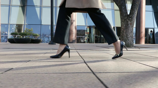 这个女人穿着高跟鞋，走在城市建筑的街道上视频下载