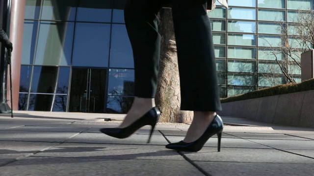 这个女人穿着高跟鞋，走在城市建筑的街道上视频素材