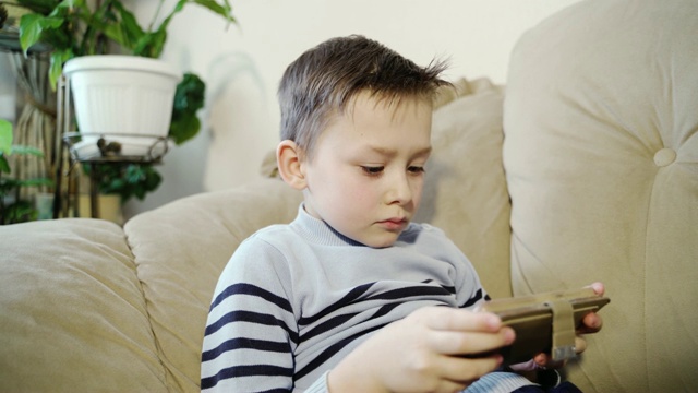 小男孩在玩平板电脑游戏。视频素材