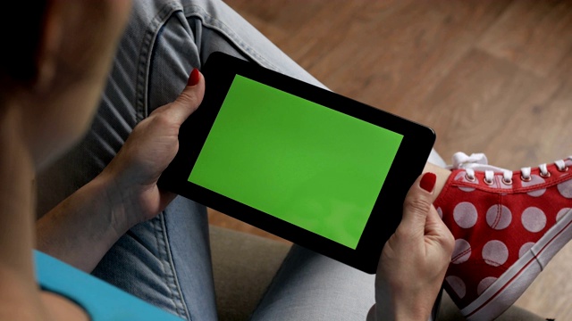 女孩在用平板电脑。女人手里拿着平板电脑的绿屏是绿屏，男人手里拿着智能手机的绿屏是色度键，背景是白色。技术。视频素材
