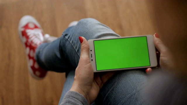 女孩在用手机。女人手里拿着智能手机的绿屏是绿屏，男人手里拿着智能手机的绿屏是色度键，背景是白色。技术的概念。视频素材