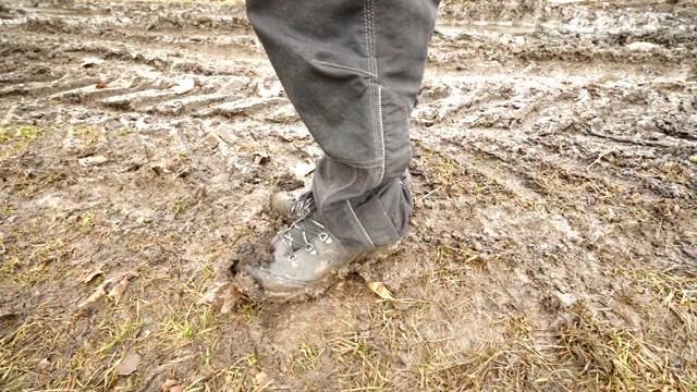 穿着泥泞的登山靴在土路上的男子徒步旅行者视频素材
