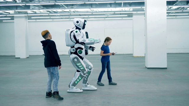 两个孩子正在控制一个人形机器人的行走过程视频下载