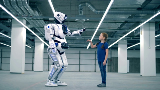 一个人形机器人正在和一个小女孩击掌视频素材