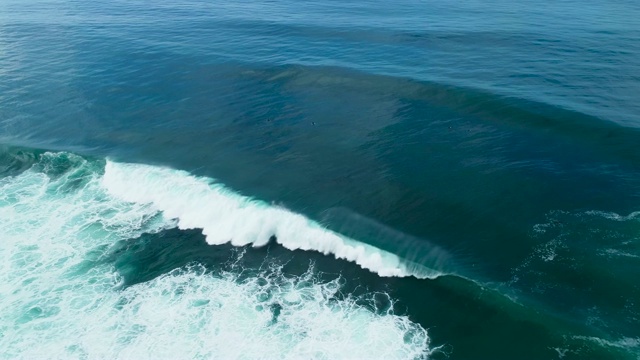 从上到下的鸟瞰图，巨大的海浪撞击在阳光明媚的一天视频素材