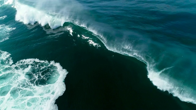 巨大的蓝色海浪撞击在阳光明媚的一天的慢镜头鸟瞰图视频素材
