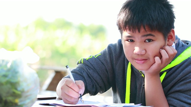 亚洲男孩做写作学习作业考试在书桌上在家户外自学教室。教育学习理念。4K视频素材