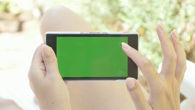 休闲在露天躺椅上的女人用绿色屏幕平板电脑4K 2160p 30fps超高清视频-女性手持绿色屏幕色键手机在海滩上4K 3840X2160超高清视频视频下载
