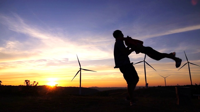 日落时分，父亲和女儿在风力涡轮机农场里纺纱视频素材