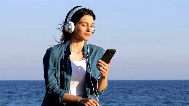 在海滩上听着音乐放松的女人视频素材