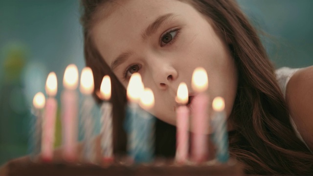 美丽的女孩吹蜡烛火焰在生日蛋糕的慢镜头。生日快乐视频素材