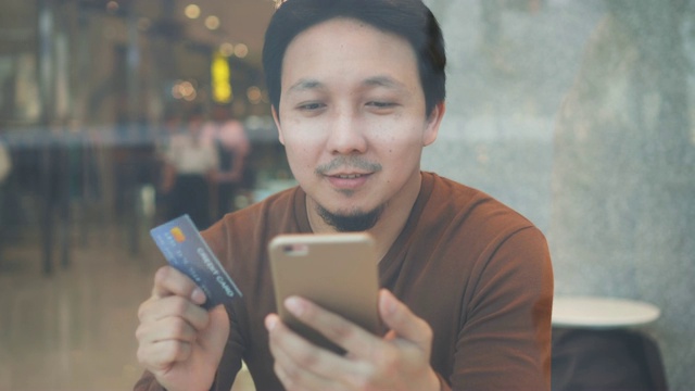 4k视频场景的亚洲人使用信用卡和手机在线购物无现金在联合办公空间在百货公司，技术钱钱包和在线支付概念，信用卡模型视频下载