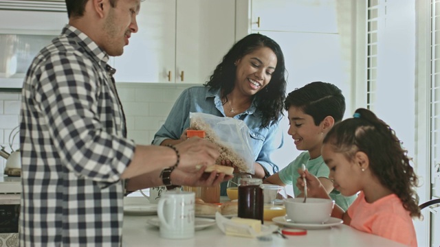 微笑的多民族家庭在厨房里吃早餐视频素材
