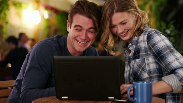 快乐的男人和女人在笔记本电脑上看视频微笑和大笑视频素材