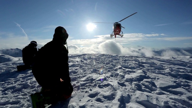 直升机把滑雪者留在山坡上，扬起一片雪云视频下载