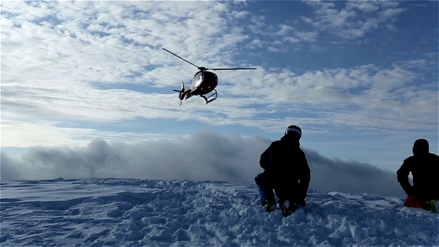 直升机把滑雪者留在山坡上，扬起一片雪云视频素材