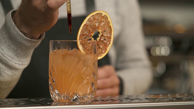 这是一个特写镜头:吧台上装满葡萄柚片的玻璃杯，一个男人的手往里面倒了一些液体视频素材