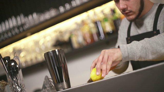 一个特写镜头，一个调酒师切一片柠檬，并把它放在吧台上的摇酒器视频素材