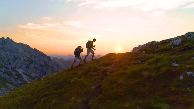 摄影:日落时分，活跃的年轻游客们在阿尔卑斯山的一座长满青草的山上徒步旅行。视频素材