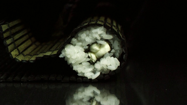 双手制作长寿司卷特写。米饭配鱼片。准备和切割传统寿司视频素材