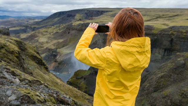 女游客探索冰岛，拍摄其峡谷的照片视频素材