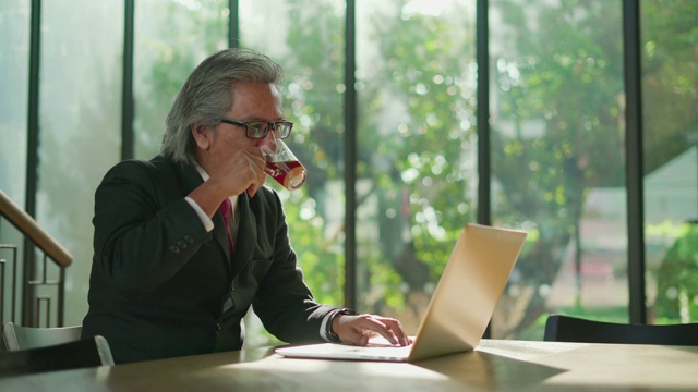 高级商人在咖啡馆里用笔记本电脑喝咖啡。视频素材