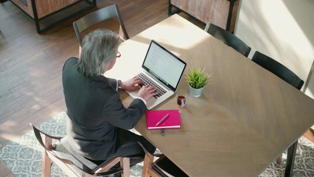 高级商人在咖啡馆里用笔记本电脑。视频素材