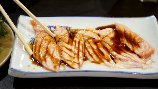 近距离用筷子挑烧在白色盘子上的鲑鱼。日本融合食物，亚洲文化。健康食品，饮食概念。视频素材