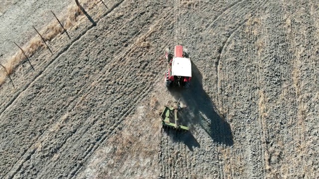 一架无人机飞过拖拉机在乡间犁地。克罗托内,意大利视频下载