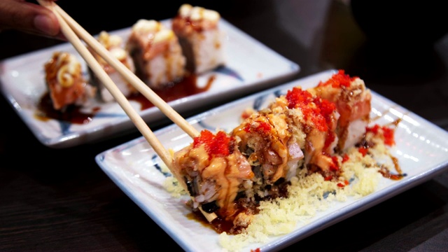 近距离筷子选择Uramaki的虾天妇罗，奶酪，鳄梨和Tobiko鱼子酱。日本融合食物，亚洲文化。健康食品，饮食概念。视频素材