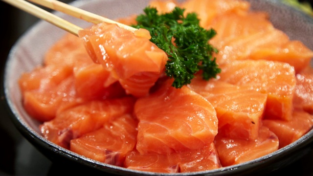 近距离用筷子挑大碗上的一组鲑鱼。日本融合食物，亚洲文化。健康食品，饮食概念。视频素材