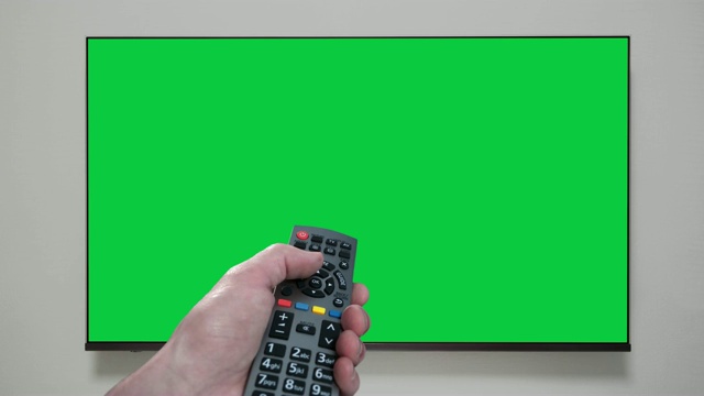 4K -手持遥控器改变频道电视。绿色的屏幕。色度键视频素材