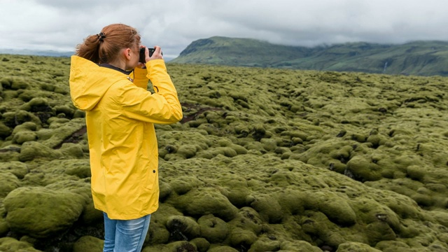 有风的一天，一名女子用相机拍下了覆盖着苔藓的熔岩地视频素材
