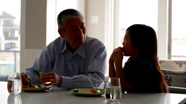 前视图可爱的亚洲孙女和老祖父吃食物的饭桌4k视频下载