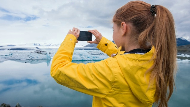 一名女子用智能手机拍摄冰川湖中漂浮的冰山视频下载