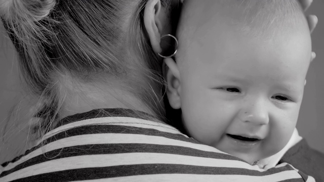 慢镜头:一个6个月大的婴儿在母亲怀里哭泣的特写。视频素材