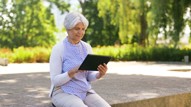 夏日公园里拿着平板电脑的老女人视频素材