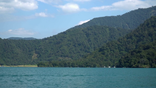 4K视点跟踪拍摄从侧面的乘客渡轮，因为它通过波浪与山，森林，白云和蓝天在日月潭，台湾。视频下载