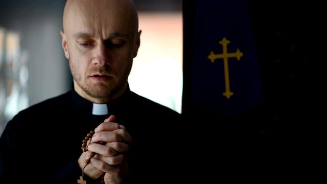 年轻的天主教牧师穿着黑衬衫祈祷视频下载