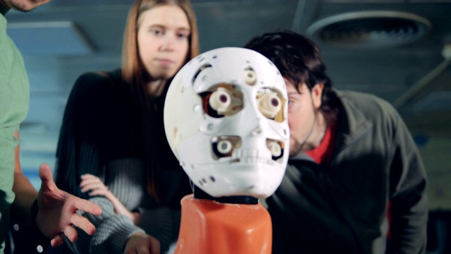 男人和女人交谈，检查一个机器人的头，近距离。视频素材