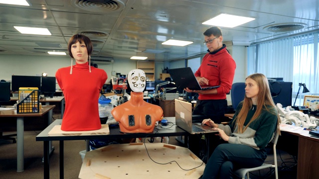 男人和女人控制一个机器人，用笔记本电脑，特写。视频素材